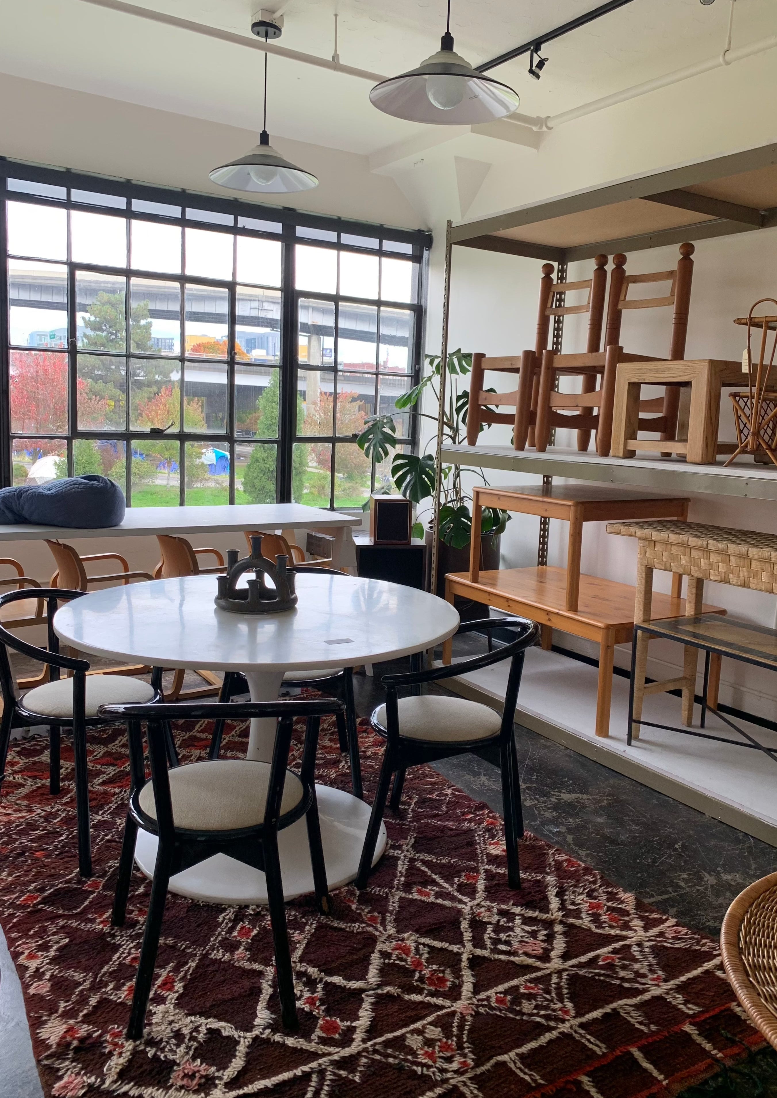 burnt reds and brown rug under tulip white table with modern chairs in contemporary loft apartment with large windows