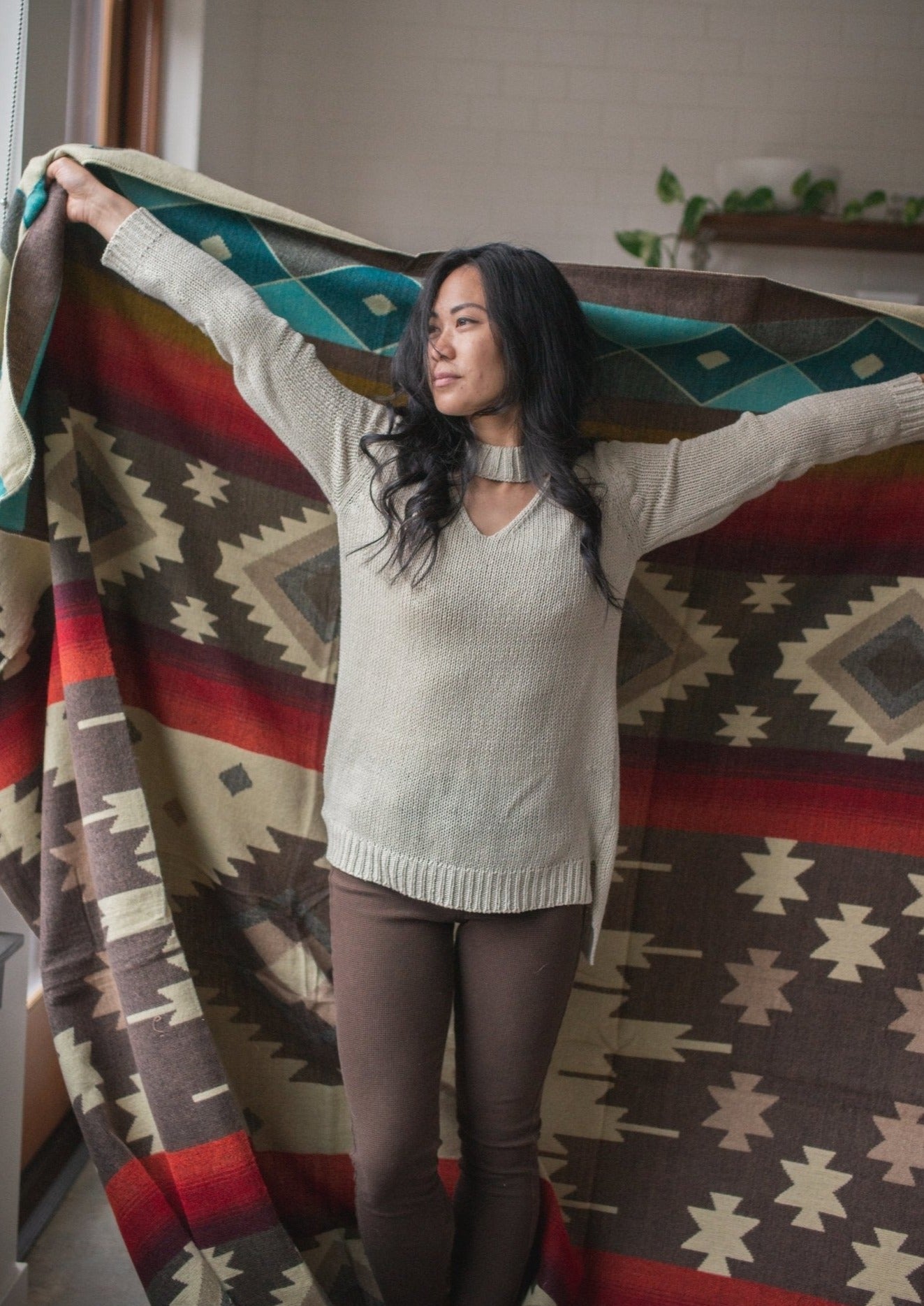 Asian girls arms are wide open holding her cozy alpaca blanket made in ecuador.