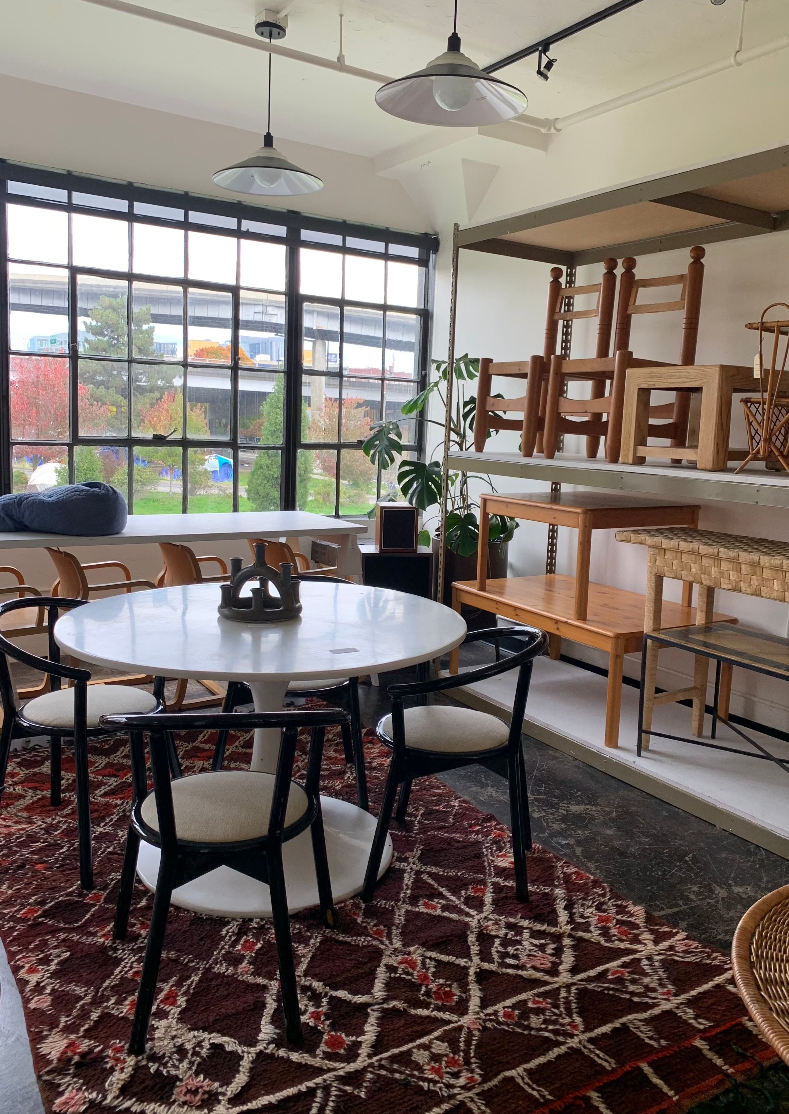 burnt reds and brown rug under tulip white table with modern chairs in contemporary loft apartment with large windows 